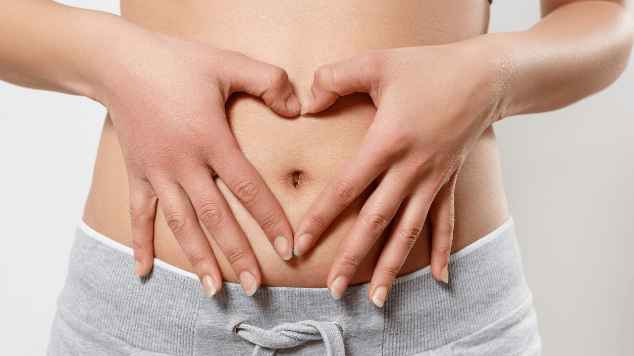 Photo of woman holding her hands in a heart over abdomen.
